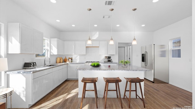 kitchen with stainless steel fridge with ice dispenser, white cabinetry, sink, and a kitchen island