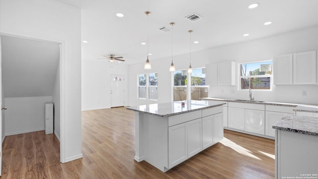 kitchen with white cabinets, a kitchen island, and ceiling fan