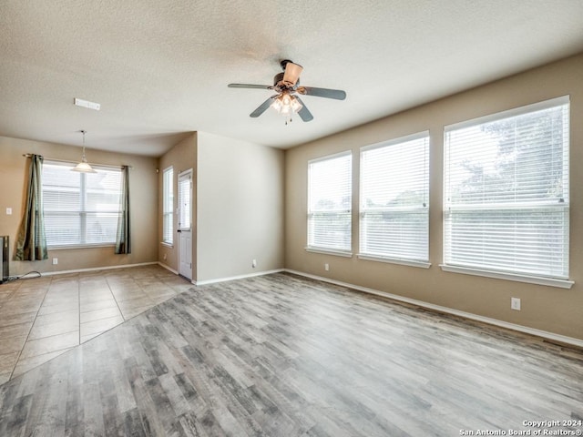 unfurnished room with ceiling fan, light hardwood / wood-style floors, and a textured ceiling