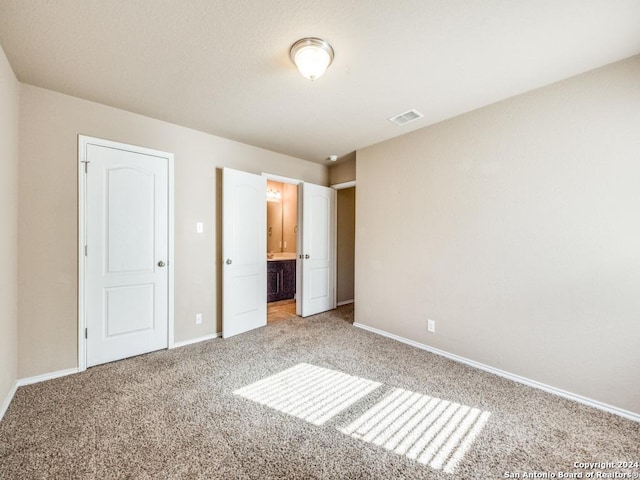 unfurnished bedroom featuring light carpet and connected bathroom