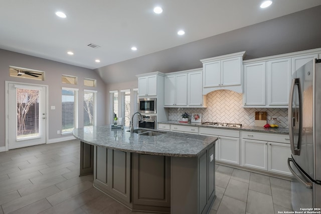 kitchen with white cabinetry, a kitchen island with sink, lofted ceiling, and appliances with stainless steel finishes