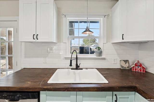 kitchen featuring hanging light fixtures, white cabinetry, sink, and dishwashing machine