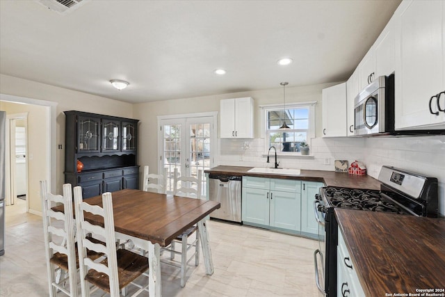 kitchen with wood counters, french doors, sink, decorative backsplash, and appliances with stainless steel finishes