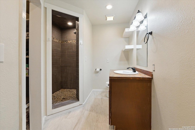 bathroom with vanity, toilet, and a tile shower