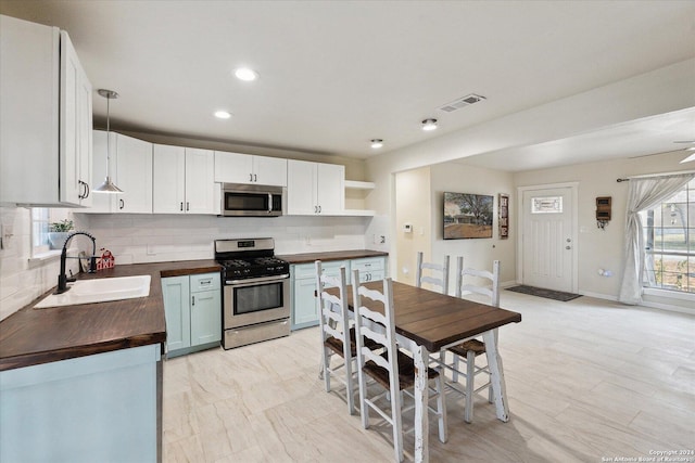 kitchen featuring butcher block countertops, white cabinetry, pendant lighting, and appliances with stainless steel finishes