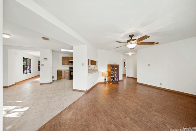 unfurnished living room featuring ceiling fan and light wood-type flooring