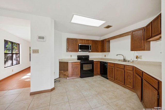 kitchen featuring black appliances, light tile patterned floors, and sink