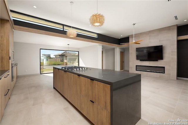 kitchen featuring decorative light fixtures, stainless steel gas stovetop, a spacious island, and ceiling fan