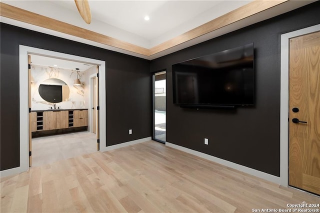 empty room with beamed ceiling and light hardwood / wood-style floors