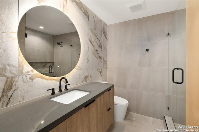 bathroom featuring tile patterned floors, toilet, vanity, a shower with shower door, and tile walls