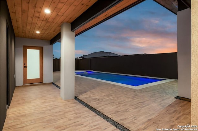 pool at dusk with a patio area