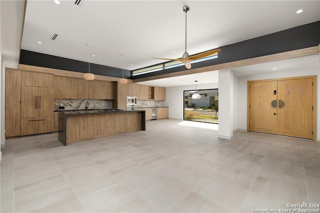 kitchen featuring decorative light fixtures, a center island, stainless steel microwave, and tasteful backsplash