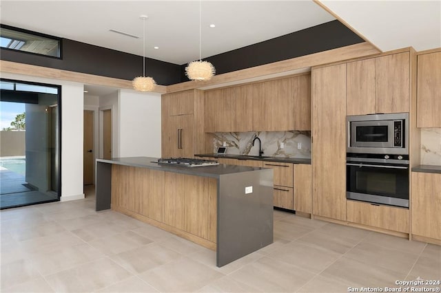 kitchen featuring appliances with stainless steel finishes, light brown cabinetry, tasteful backsplash, pendant lighting, and a kitchen island