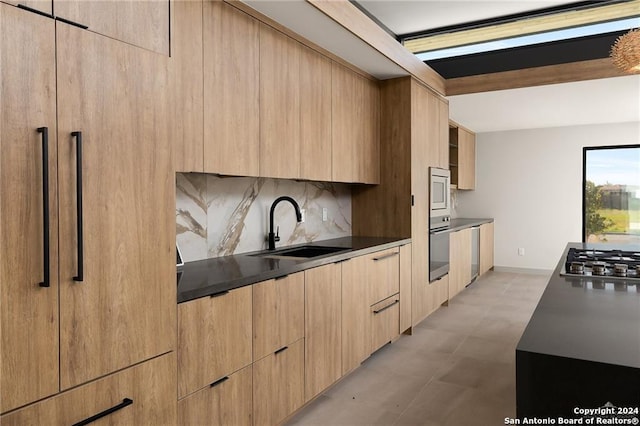 kitchen with backsplash, light brown cabinetry, sink, and appliances with stainless steel finishes