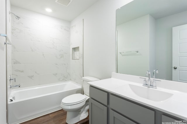 full bathroom featuring vanity, hardwood / wood-style floors, tiled shower / bath combo, and toilet