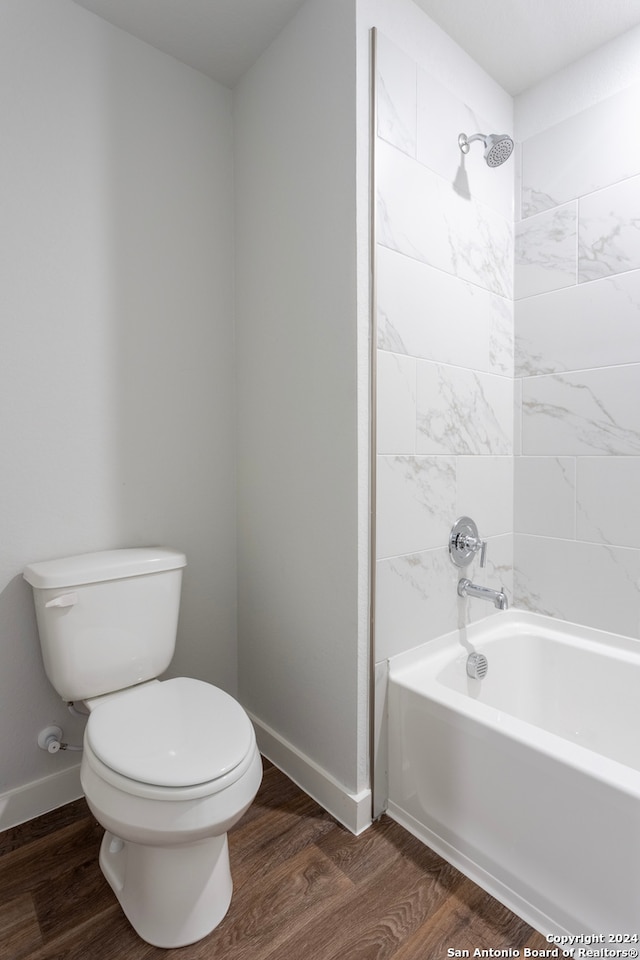 bathroom featuring hardwood / wood-style floors, toilet, and tiled shower / bath