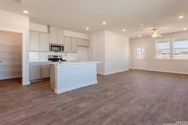 kitchen with ceiling fan, tasteful backsplash, an island with sink, gray cabinets, and appliances with stainless steel finishes