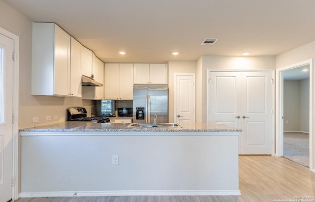 kitchen featuring light stone countertops, sink, light hardwood / wood-style flooring, white cabinets, and appliances with stainless steel finishes