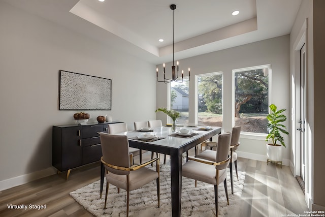 dining area featuring a raised ceiling, hardwood / wood-style floors, and a chandelier