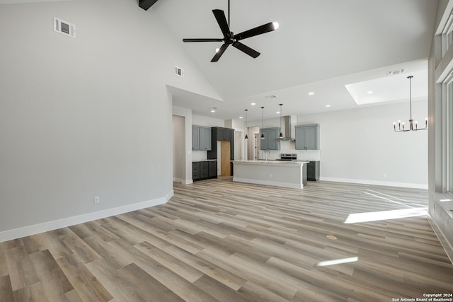 unfurnished living room featuring high vaulted ceiling, light hardwood / wood-style floors, and ceiling fan with notable chandelier