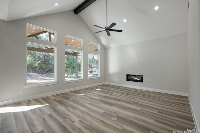 unfurnished living room featuring beam ceiling, ceiling fan, high vaulted ceiling, heating unit, and light hardwood / wood-style floors