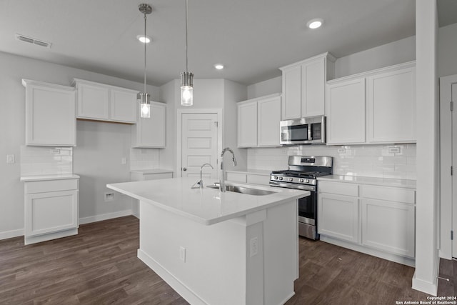 kitchen featuring appliances with stainless steel finishes, sink, white cabinets, hanging light fixtures, and an island with sink