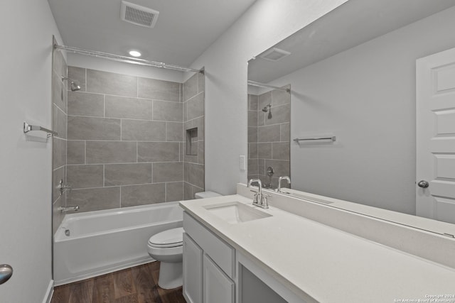 full bathroom with toilet, vanity, wood-type flooring, and tiled shower / bath