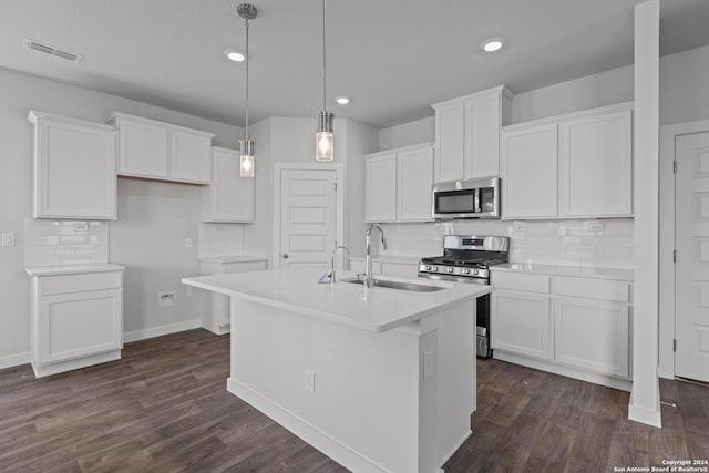 kitchen featuring appliances with stainless steel finishes, a kitchen island with sink, sink, decorative light fixtures, and white cabinets