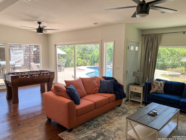 living room with a textured ceiling, ceiling fan, and dark wood-type flooring