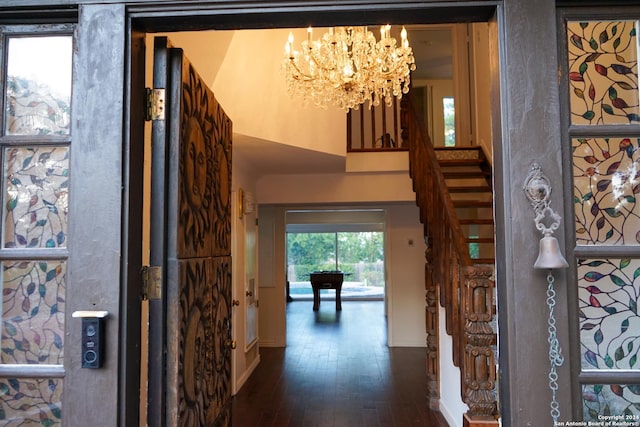 foyer with dark hardwood / wood-style flooring, a towering ceiling, and a chandelier