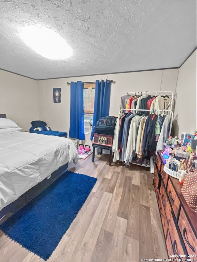 bedroom featuring hardwood / wood-style floors, a textured ceiling, and a closet