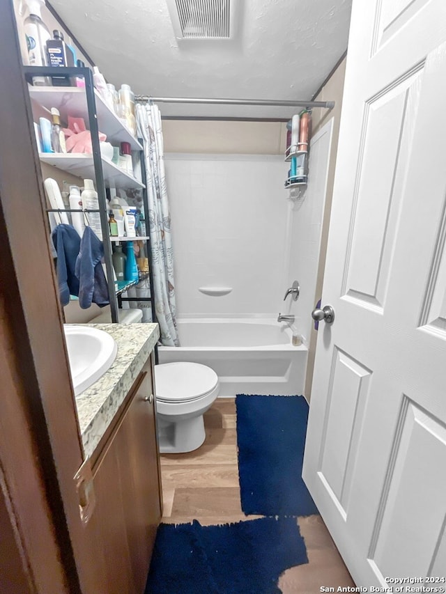 full bathroom with shower / bath combo, wood-type flooring, a textured ceiling, toilet, and vanity