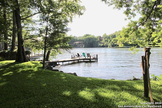 view of dock with a lawn and a water view