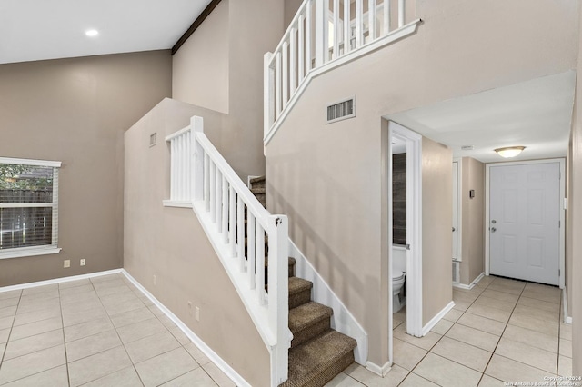 staircase with tile patterned flooring and a towering ceiling