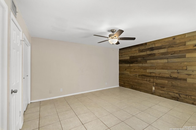 unfurnished room featuring wooden walls, ceiling fan, and light tile patterned floors