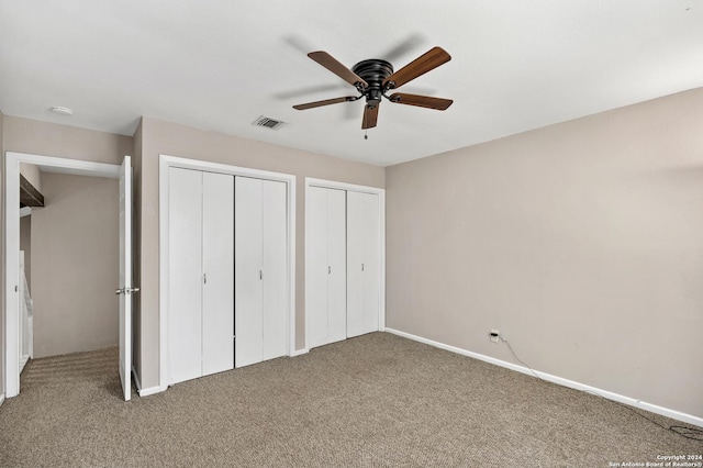 unfurnished bedroom with carpet flooring, ceiling fan, and multiple closets