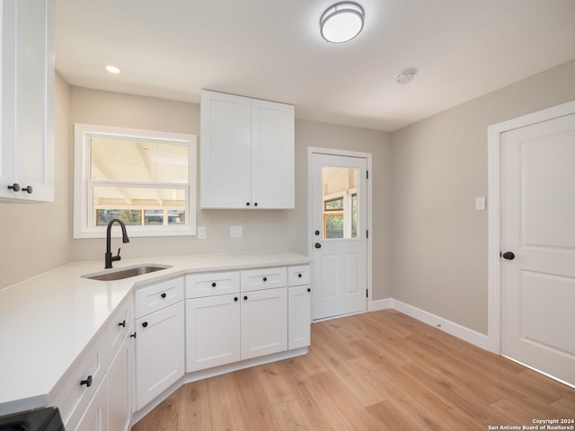 kitchen featuring white cabinetry, sink, and light hardwood / wood-style flooring