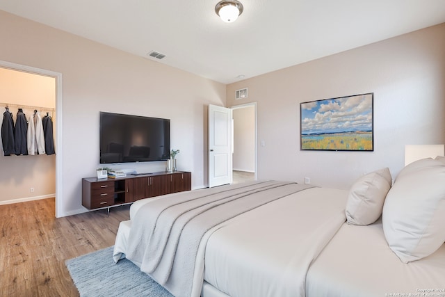 bedroom featuring a walk in closet, light hardwood / wood-style flooring, and a closet