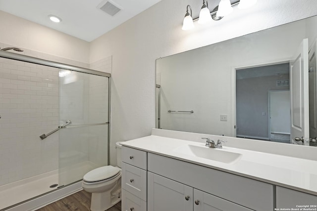 bathroom featuring wood-type flooring, vanity, toilet, and walk in shower