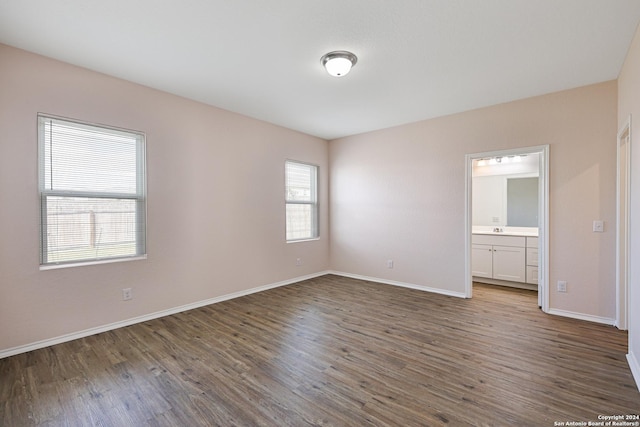 unfurnished bedroom with ensuite bath, sink, and dark wood-type flooring