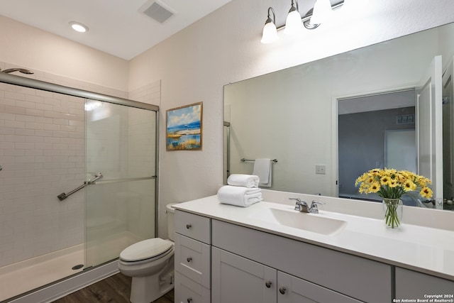 bathroom with hardwood / wood-style flooring, vanity, toilet, and walk in shower