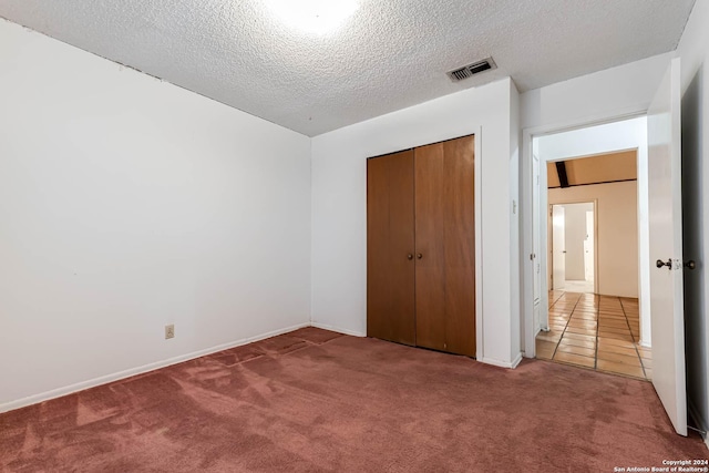 unfurnished bedroom featuring a textured ceiling, carpet floors, and a closet