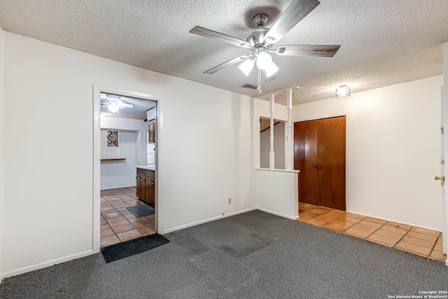 carpeted spare room featuring ceiling fan and a textured ceiling