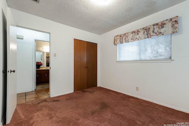 unfurnished bedroom featuring a closet, carpet, and a textured ceiling