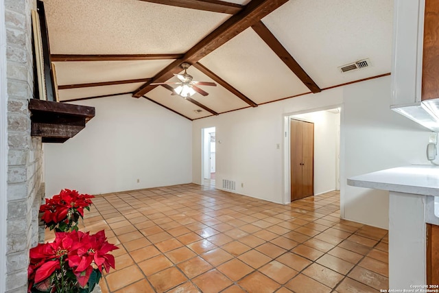 unfurnished living room featuring vaulted ceiling with beams, ceiling fan, light tile patterned floors, and a textured ceiling