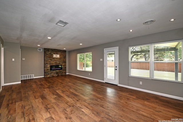 unfurnished living room with a stone fireplace and dark hardwood / wood-style floors