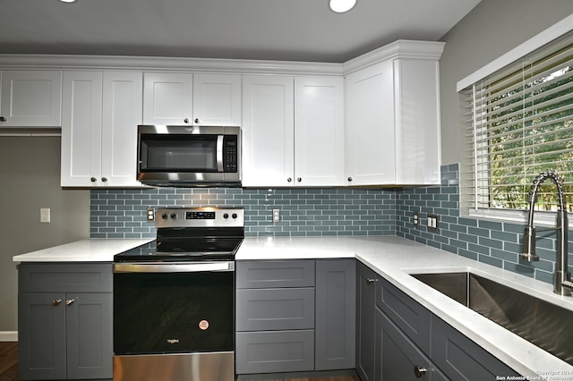 kitchen with backsplash, gray cabinetry, stainless steel appliances, sink, and white cabinets