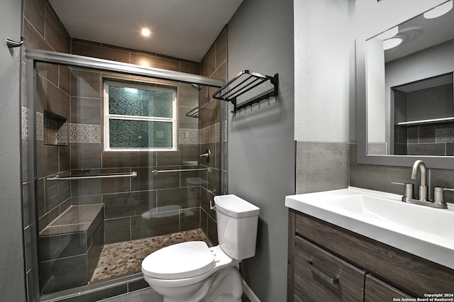 bathroom with vanity, toilet, and a shower with door