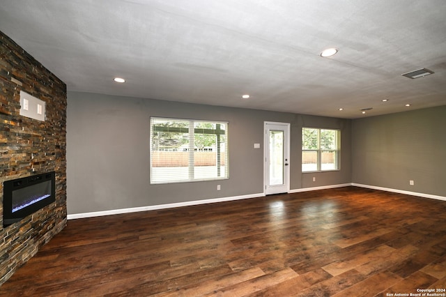 unfurnished living room featuring a stone fireplace and dark hardwood / wood-style flooring