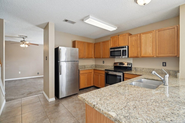 kitchen with sink, ceiling fan, light stone countertops, light tile patterned floors, and appliances with stainless steel finishes